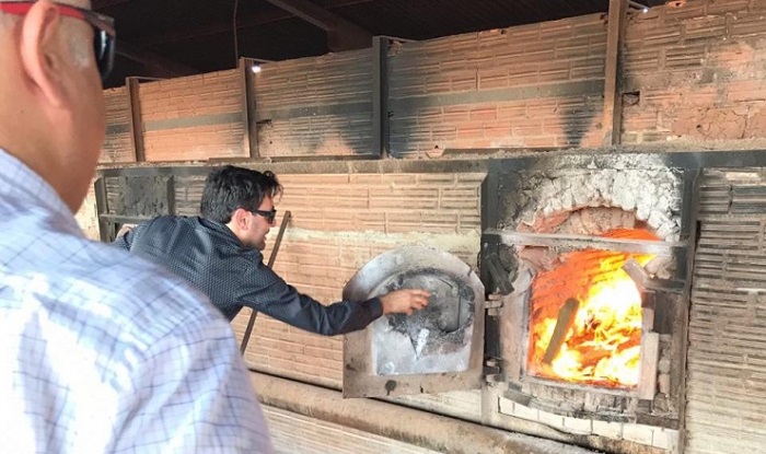 Pessoas com pacote de produtos entorpecentes nas mãos e jogando esse pacote dentro de um forno