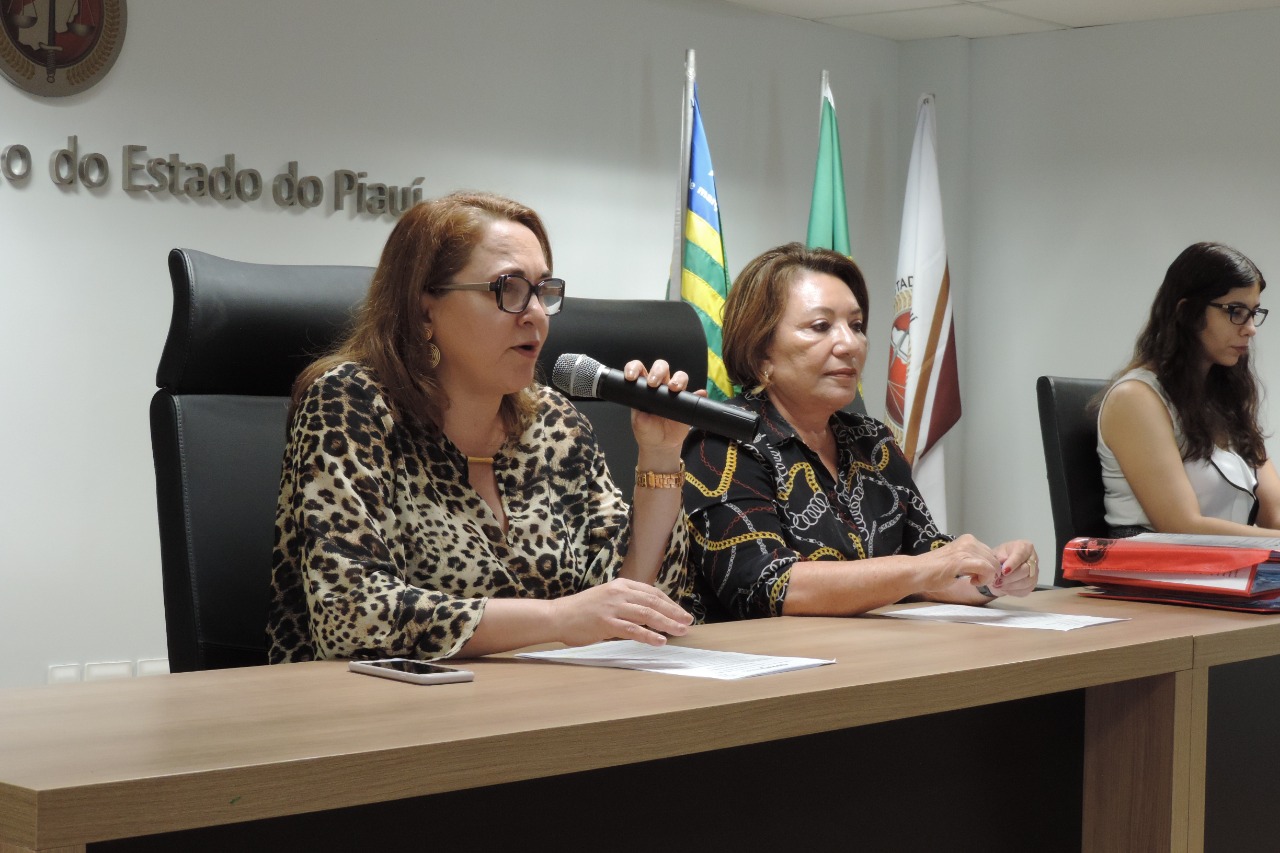 Três mulheres sentadas atrás de uma bancada 