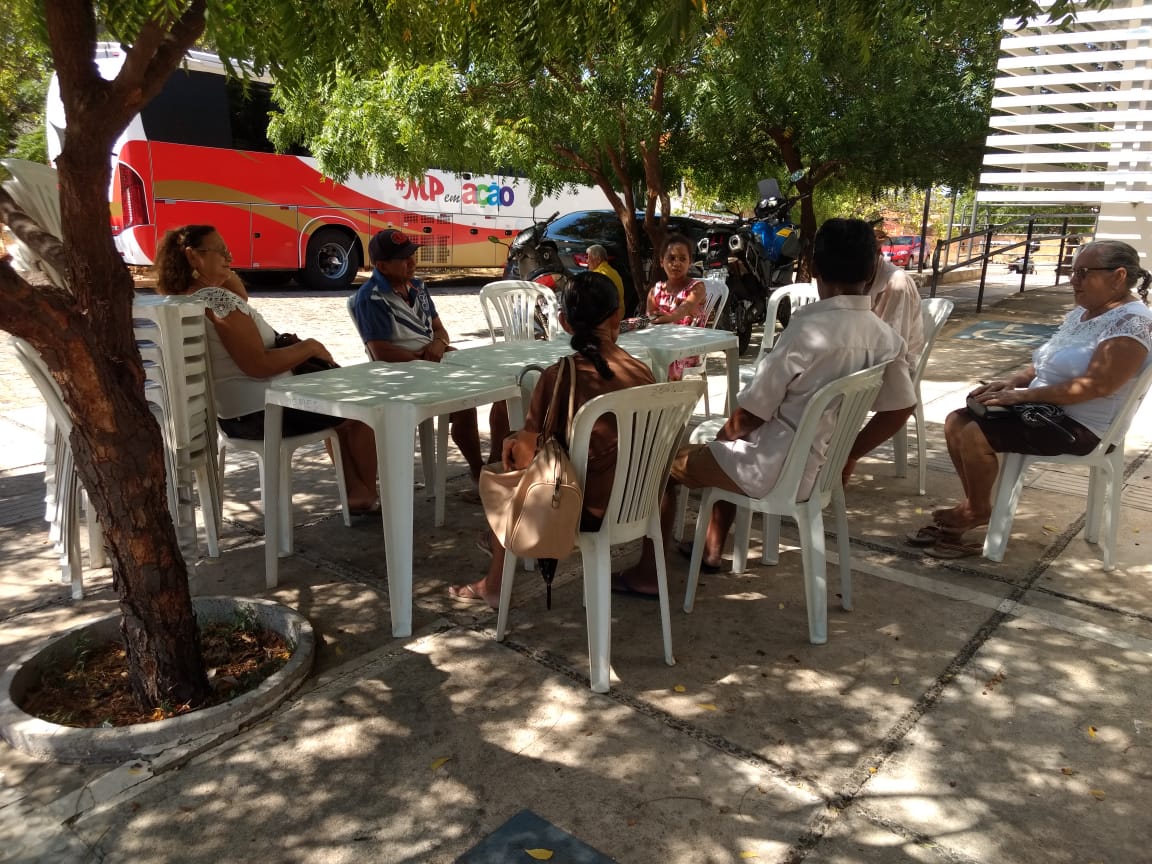Pessoas sentadas do lado de fora do ônibus do Procon Itinerante aguardando atendimento 