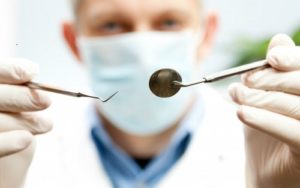 dentista segurando instrumentos na boca de uma paciente