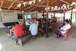 Pessoas sentadas em uma área coberta assistindo a uma palestra