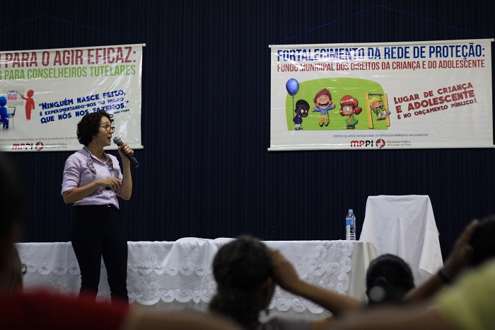 Mulher de pé falando com microfone nas mãos 