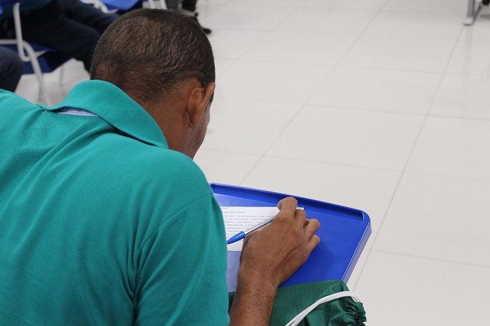 Homem sentado escrevendo em um caderno 