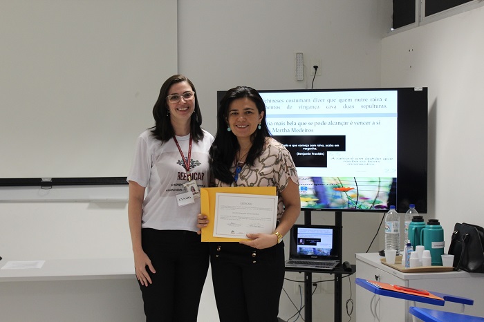 Duas mulheres de pé segurando um certificado 