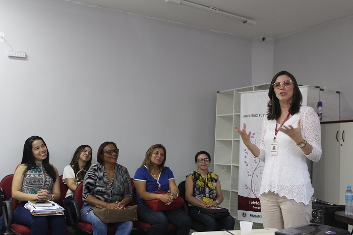 Mulher de pé falando para plateia 