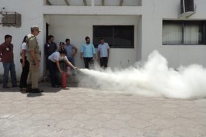 Pessoas de pé observando outra que manipula um extintor de incêndio