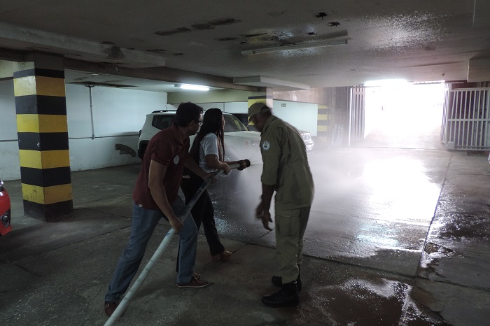 Pessoas de pé segurando uma mangueira de combate de incêndio 