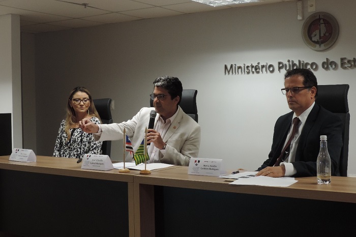 Três pessoas sentadas atrás de uma mesa 