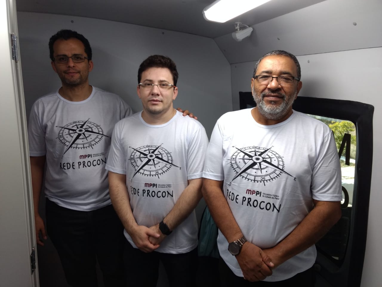 Três pessoas de pé sorrindo 