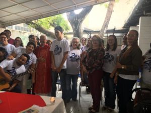 Promotora de Justiça em solenidade, rodeada por muitas pessoas que trajam camisetas com o dizeres
