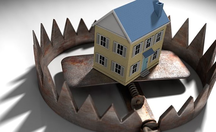 Maquete de casa no centro de armadilha, simbolizando os perigos de golpe no mercado imobiliário.
