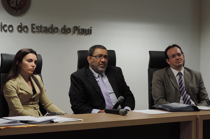 Três pessoas sentadas um do lado do outro atrás de uma mesa 