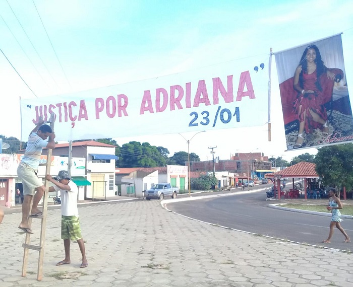 Pessoas pendurando uma faixa com a seguinte frase: Justiça por Adriana