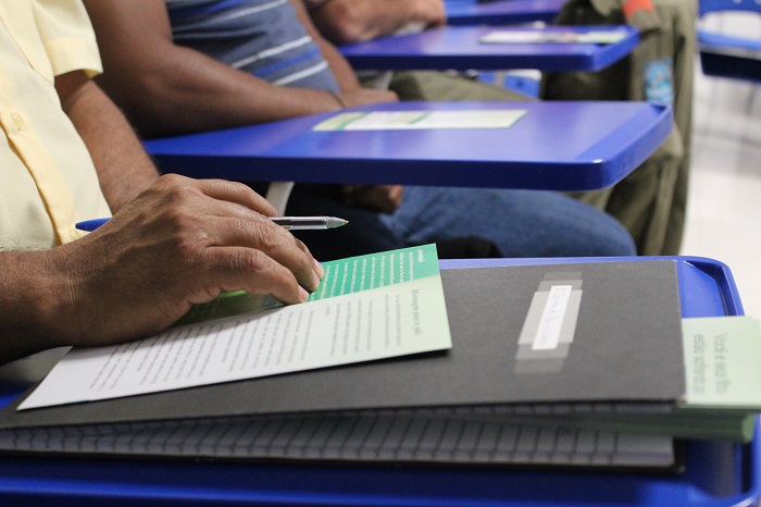 Pessoas com caderno sobre uma mesa e a mão em cima 