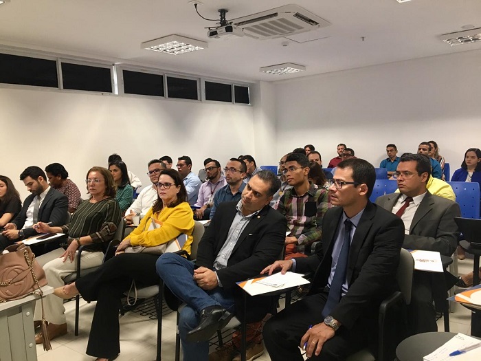 Pessoas sentadas em sala de aula assistindo palestra