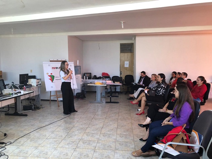Pessoas sentadas em auditório assistindo palestra 