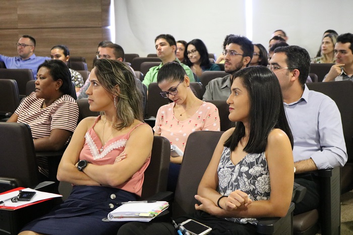 Homem gesticulando de pé e pessoas sentadas 