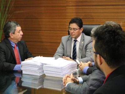 Pessoas sentadas analisando processos de denúncias