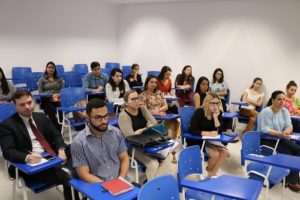 Pessoas sentadas em sala de aula assistindo treinamento