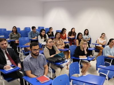Pessoas sentadas em sala de aula assistindo treinamento