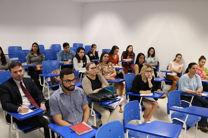 Pessoas sentadas em sala de aula assistindo treinamento