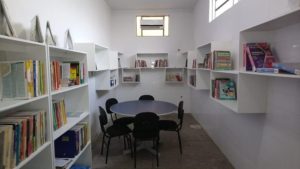 Fotos da estrutura da biblioteca. No espaço estão mesas, estantes, cadeiras e os livros obtidos com as doações