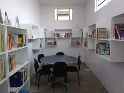 Fotos da estrutura da biblioteca. No espaço estão mesas, estantes, cadeiras e os livros obtidos com as doações