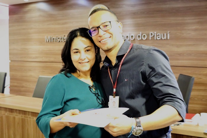 Homem e mulher sorrindo segurando uma folha de papel