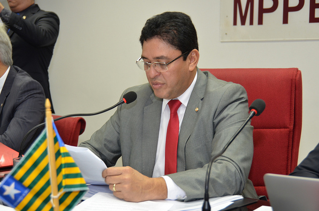 Homem segurando um papel enquanto fala 