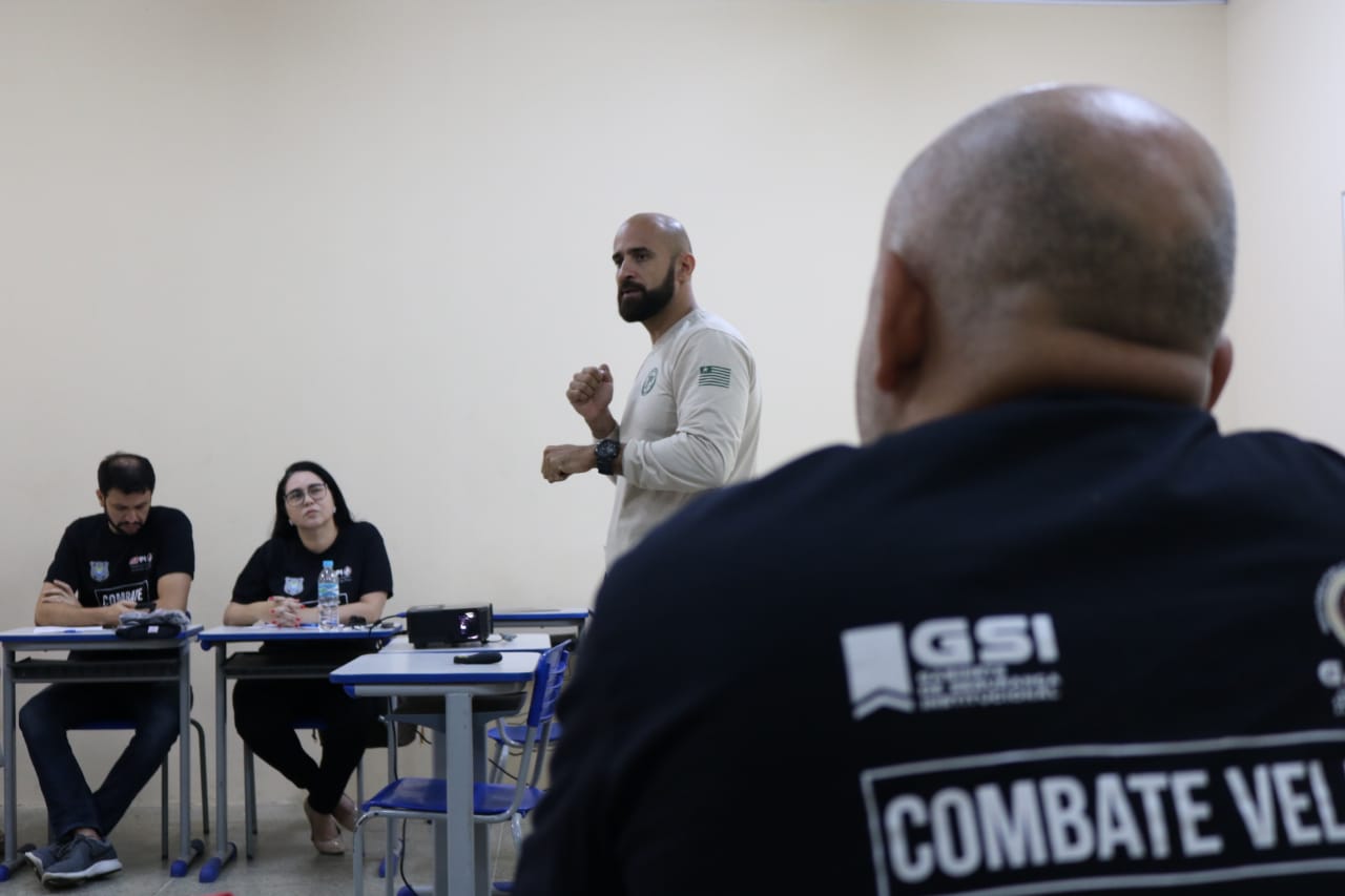 Homem de pé gesticulando com pessoas sentadas observando-o
