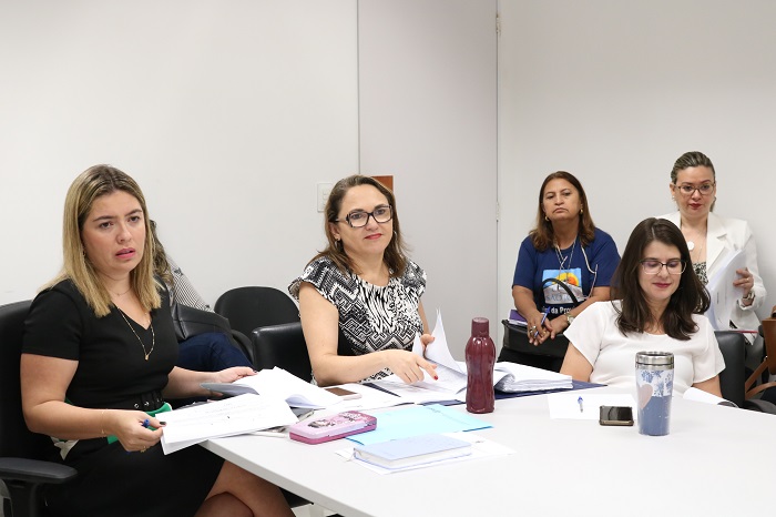 Três pessoas sentadas atrás de uma mesa 