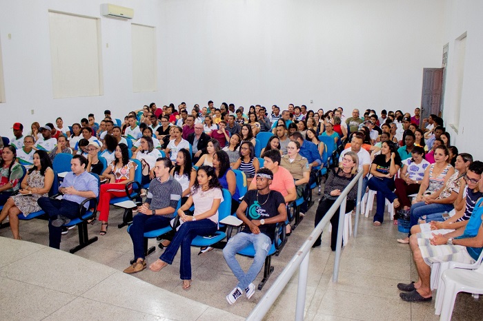 Dois homens de pé falando para a plateia que o assistem 