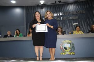 Duas mulheres de pé segurando um diploma e sorrindo para a fotografia