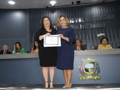 Duas mulheres de pé segurando um diploma e sorrindo para a fotografia
