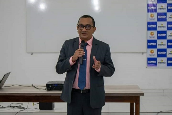 Homem de pé falando com microfone nas mãos 
