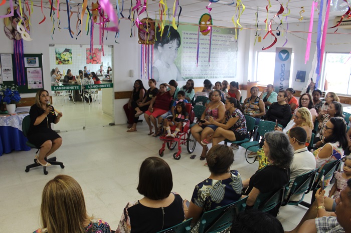 Pessoas sentadas em área aberta assistindo palestra da promotora Amparo Paz 