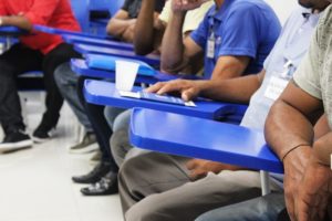Homens sentados com as mãos sobre cadeiras