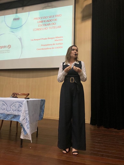 Mulher de pé falando para plateia 