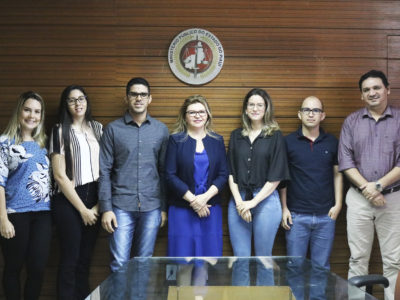 Os cinco servidores, Subprocuradora de Justiça Administrativa Carmelina Moura e o Chefe dos Recursos Humanos do MPPI Carlos Eduardo presentes na foto. Acima deles, uma moldura com a logo do MPPI.