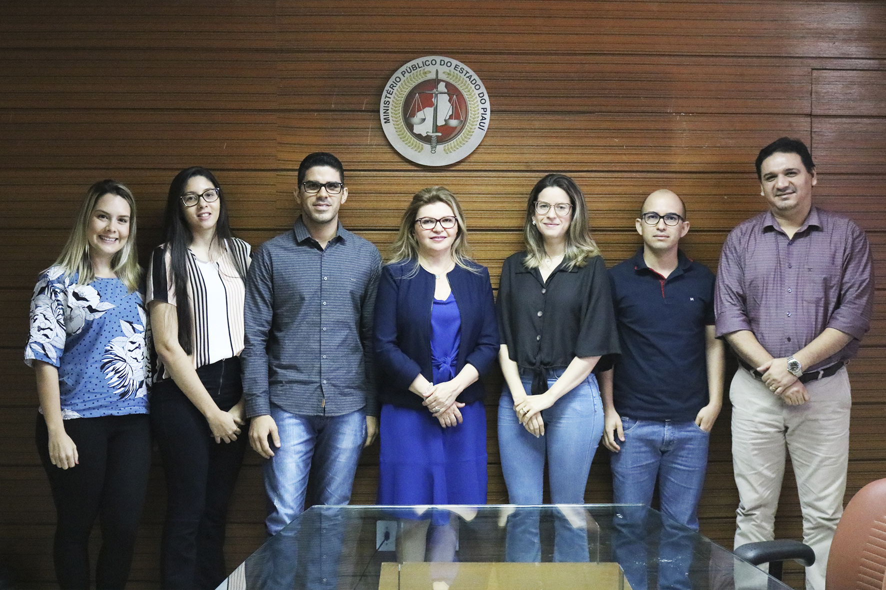 Os cinco servidores, Subprocuradora de Justiça Administrativa Carmelina Moura e o Chefe dos Recursos Humanos do MPPI Carlos Eduardo presentes na foto. Acima deles, uma moldura com a logo do MPPI.