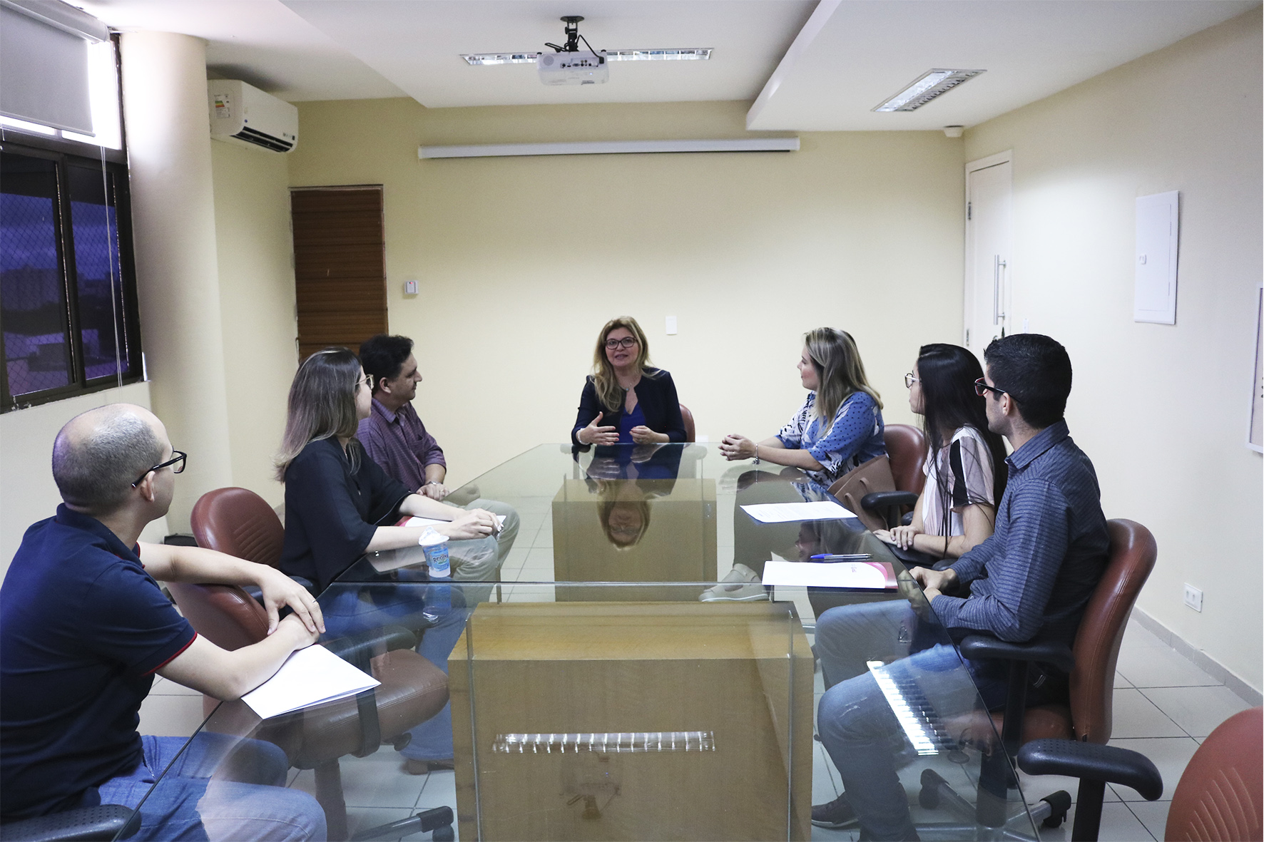 Os cinco servidores, Subprocuradora de Justiça Administrativa Carmelina Moura e o Chefe dos Recursos Humanos do MPPI Carlos Eduardo sentados na mesa