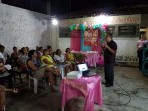 Homem em pé falando para pessoas sentadas