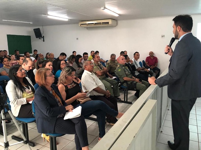 Homem de pé falando para plateia que o observa