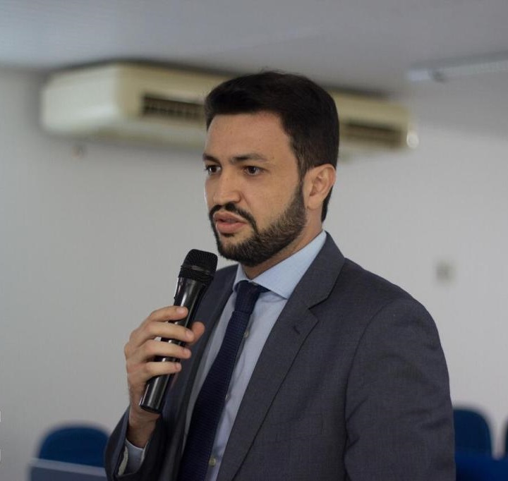 Homem de pé falando com microfone nas mãos 