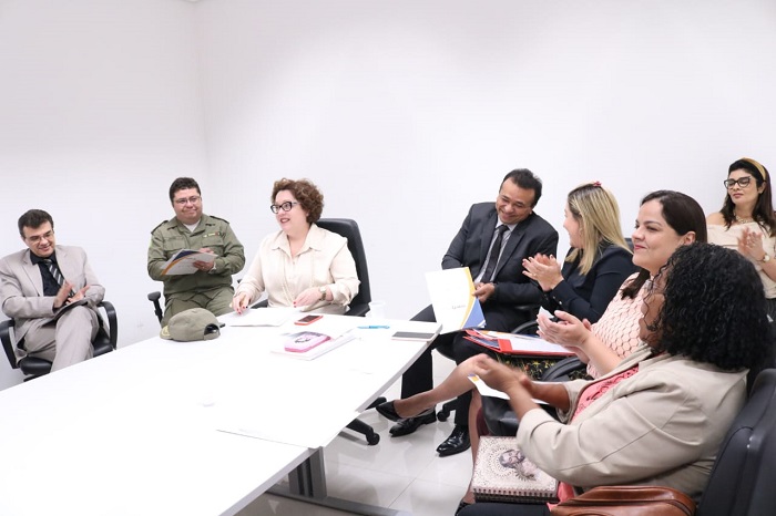Pessoas sentadas em volta de uma mesa e sorrindo durante reunião