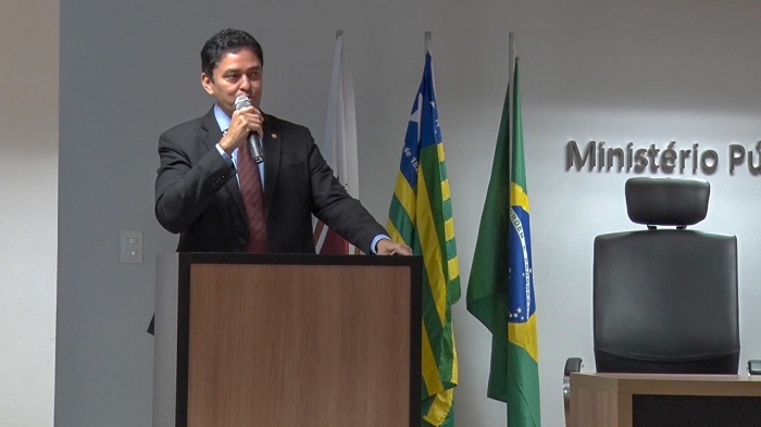 Pessoa de pé falando com microfone nas mãos 