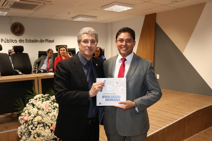 Dois homens de pé sorrindo e segurando um livro 
