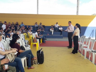 Pessoas sentadas em uma quadra assistindo uma palestra