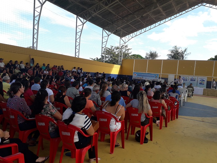 Pessoas sentadas em uma quadra assistindo uma palestra 