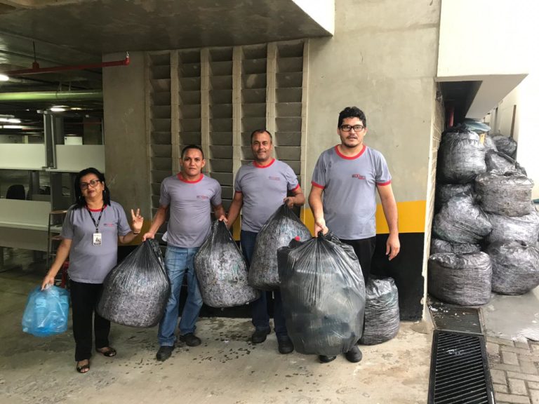 Quatro pessoas de pe segurando sacolas